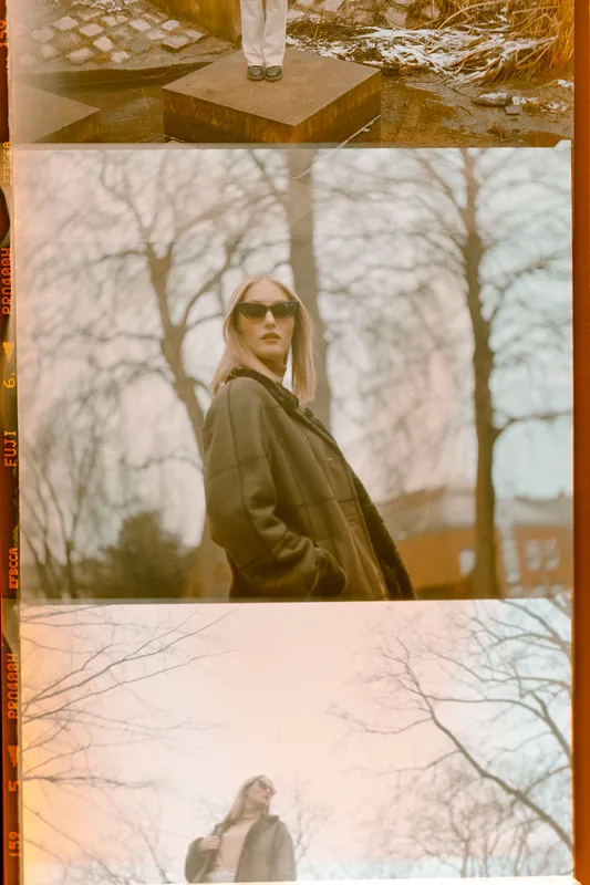 Analoge Filmstreifen mit Porträts einer Frau mit Sonnenbrille vor herbstlicher Waldkulisse.