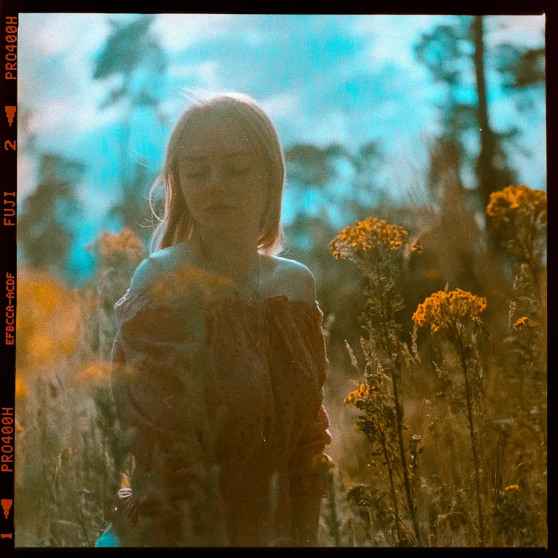 Analoges Portrait einer Frau inmitten von gelben Wildblumen.