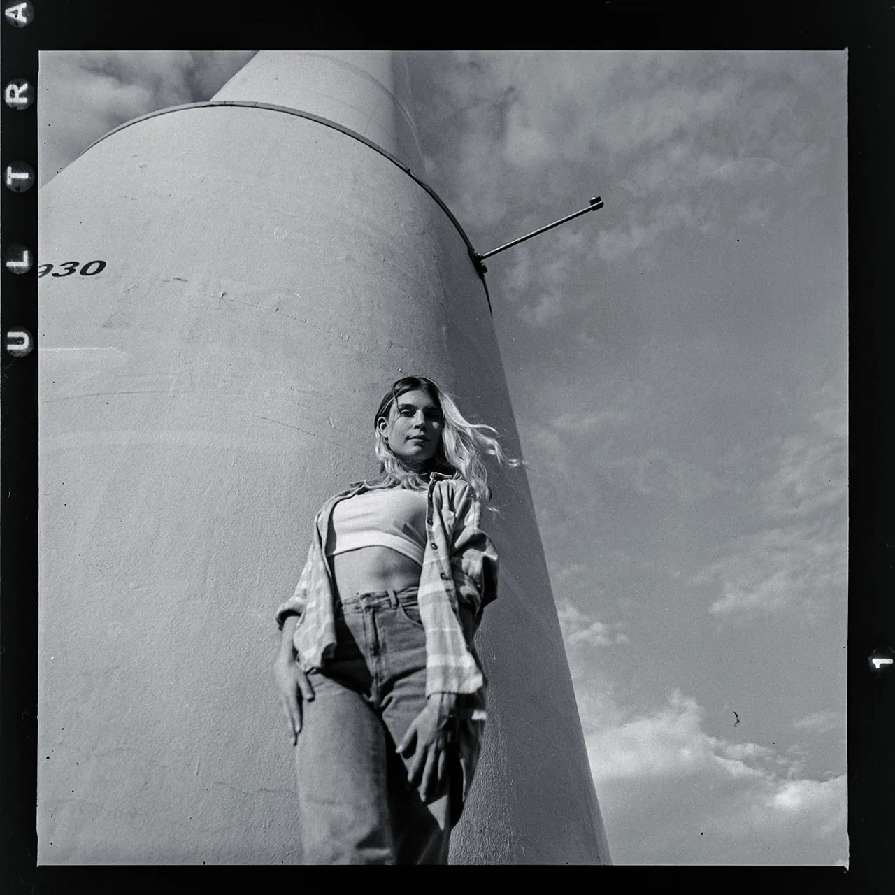 Analoges Portrait einer jungen Frau vor einem massiven, hellen