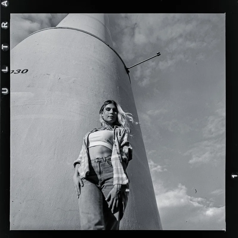 Analoges Portrait einer jungen Frau vor einem massiven, hellen