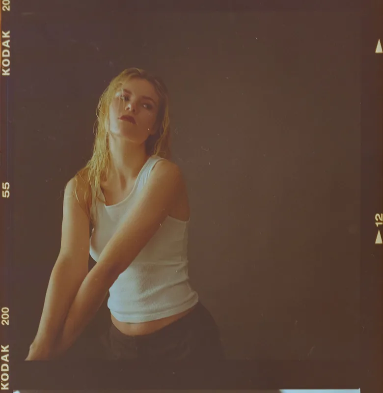 Analoges Portrait einer jungen Frau im weißen Tanktop.