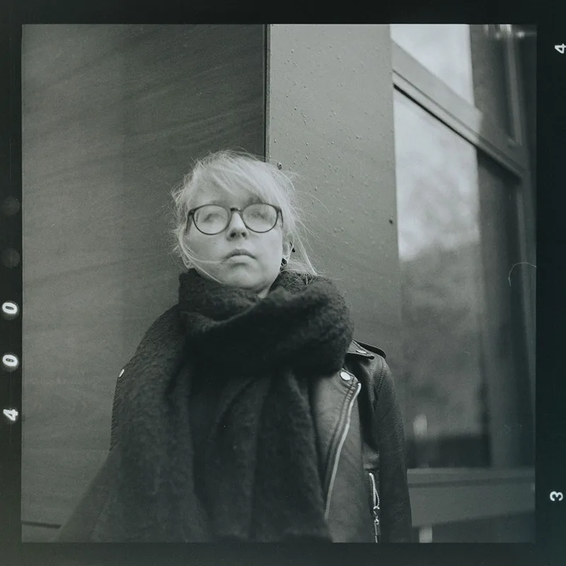 Analoges Schwarz-Weiß-Portrait einer Frau mit Brille und Schal