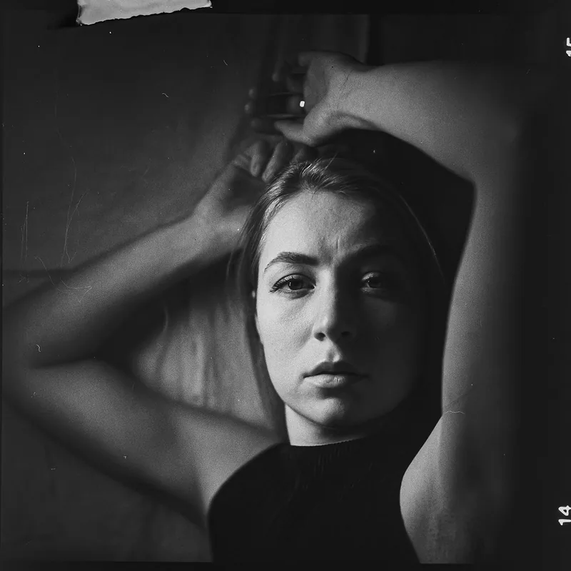 Analoges Schwarz-Weiß-Portrait einer Frau mit erhobenen Armen.