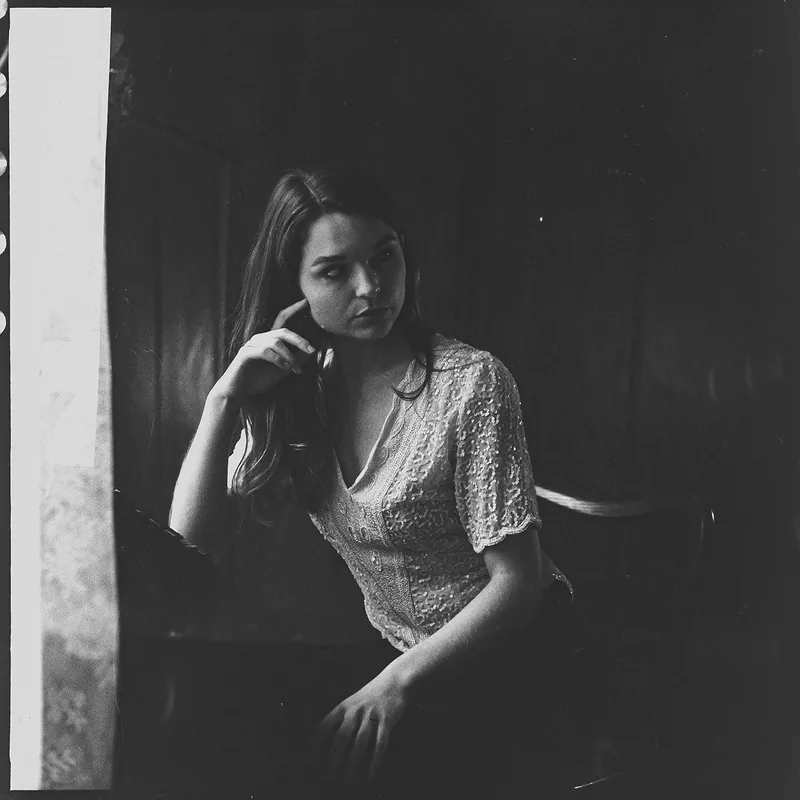 Analoges Schwarz-Weiß-Portrait einer Frau in einem hellen Spitzenoberteil.
