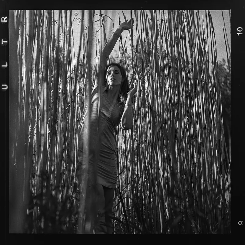 Analoges Schwarz-Weiß-Portrait einer Frau inmitten von hohem Schilf.