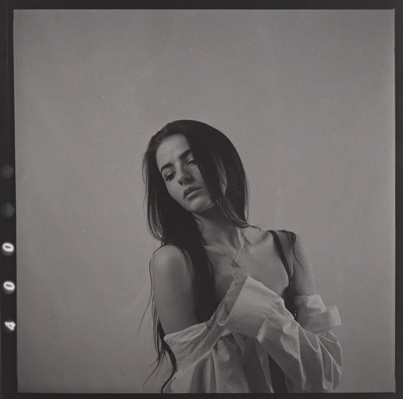 Analoges Schwarz-Weiß-Portrait einer Frau mit langem dunklem Haar und weißer Bluse.