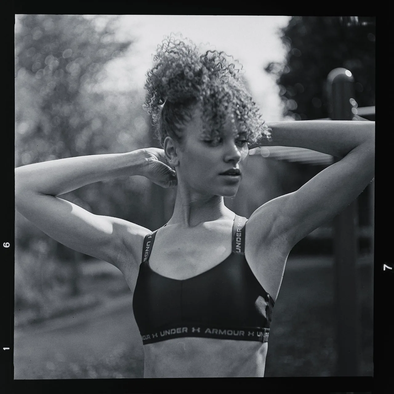 Analoges Schwarz-Weiß-Portrait einer Frau mit Locken in Sportbekleidung.