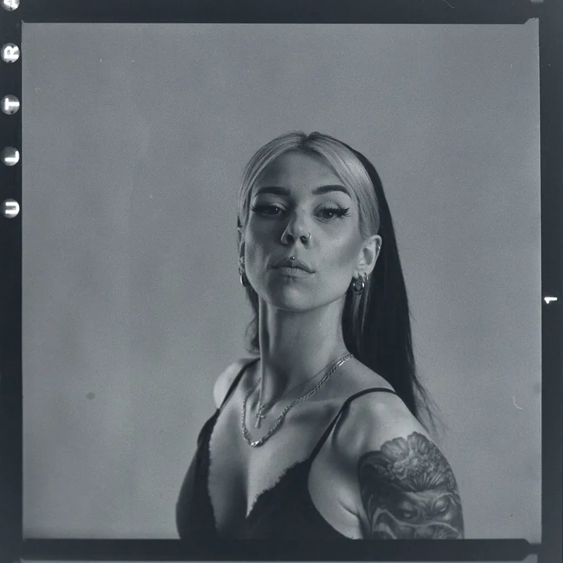 Analoges Schwarz-Weiß-Portrait einer Frau mit Nasenpiercing und Tattoo auf der Schulter.