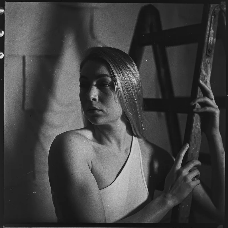 Analoges Schwarz-Weiß-Portrait einer Frau neben einer Holzleiter.