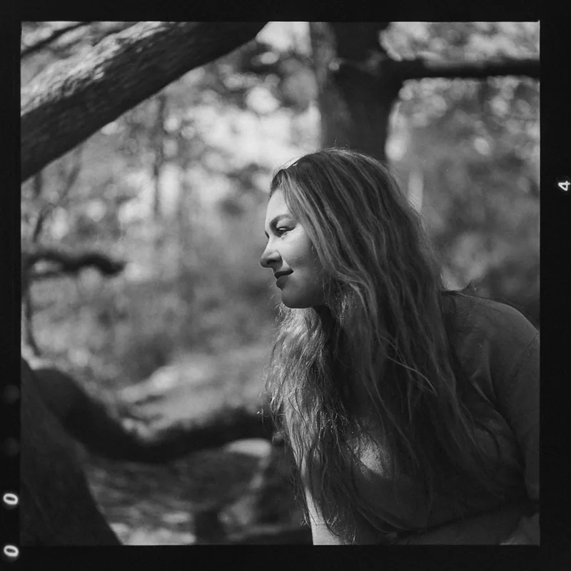 Analoges Schwarz-Weiß-Portrait einer Frau im Profil in einem Wald.