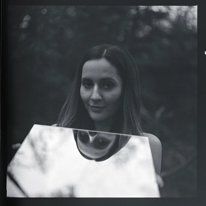 Analoges Schwarz-Weiß-Portrait einer Frau mit der Reflexion ihres Gesichts in einem Spiegel.