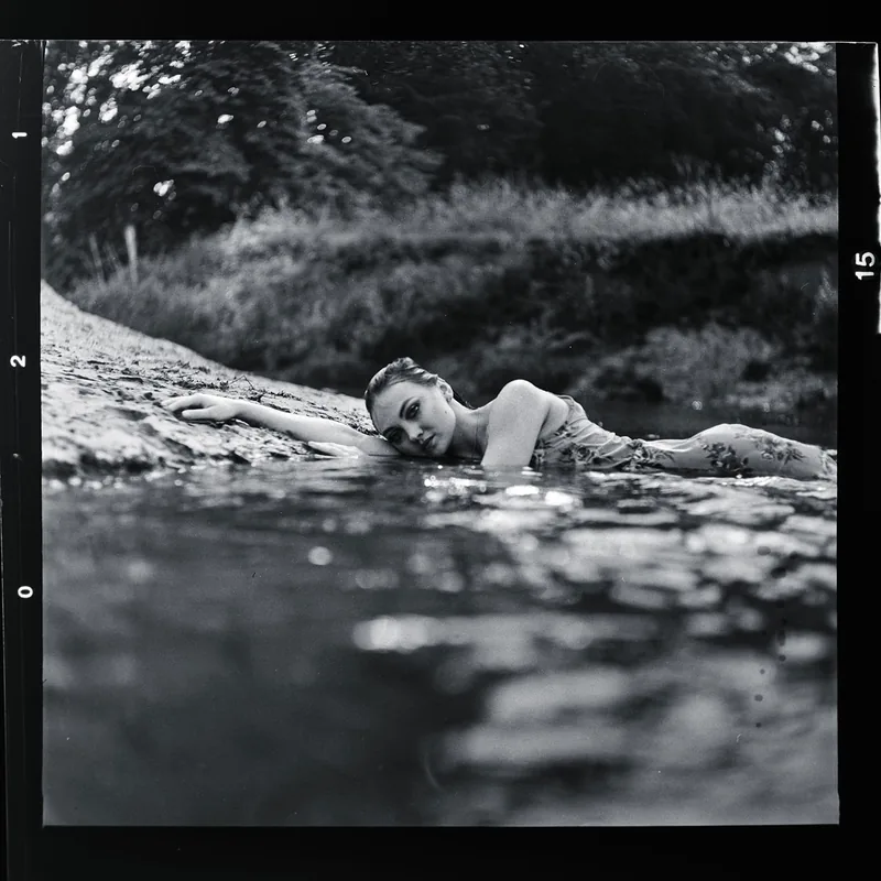 Analoges Schwarz-Weiß-Portrait einer Frau im seichten Wasser am Ufer.