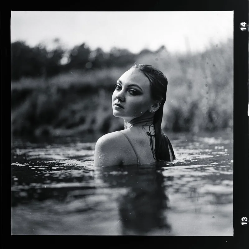 Analoges Schwarz-Weiß-Portrait einer Frau im Wasser, die über ihre Schulter blickt.