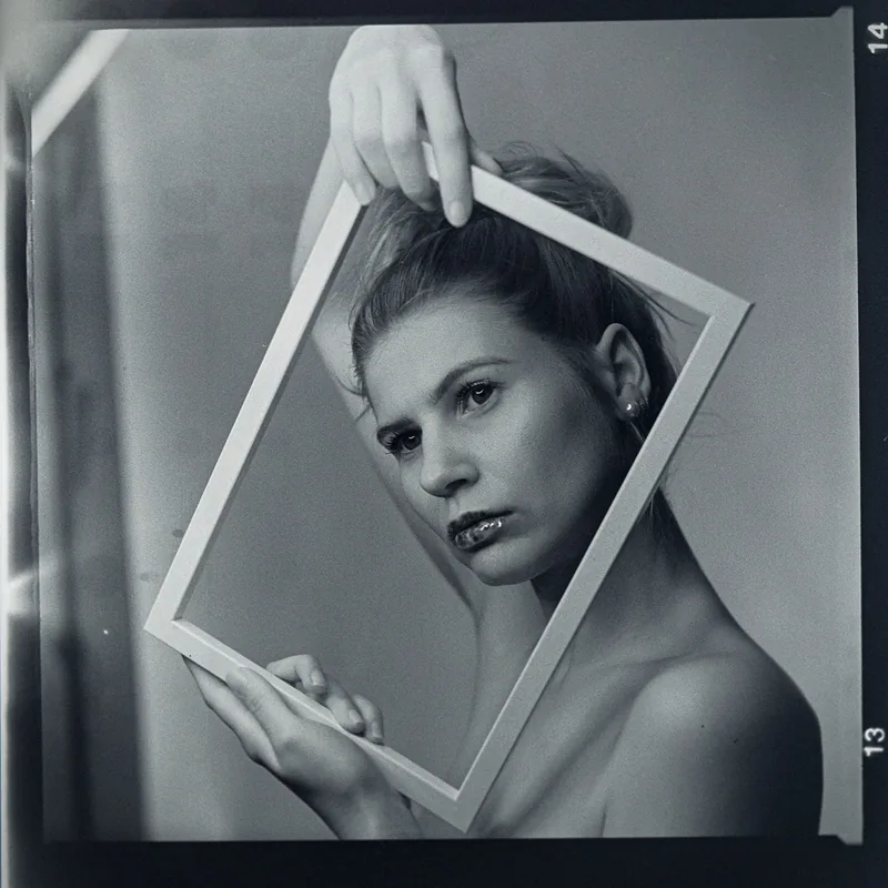 Analoges Schwarz-Weiß-Portrait einer Frau mit einem weißen Rahmen um das Gesicht.