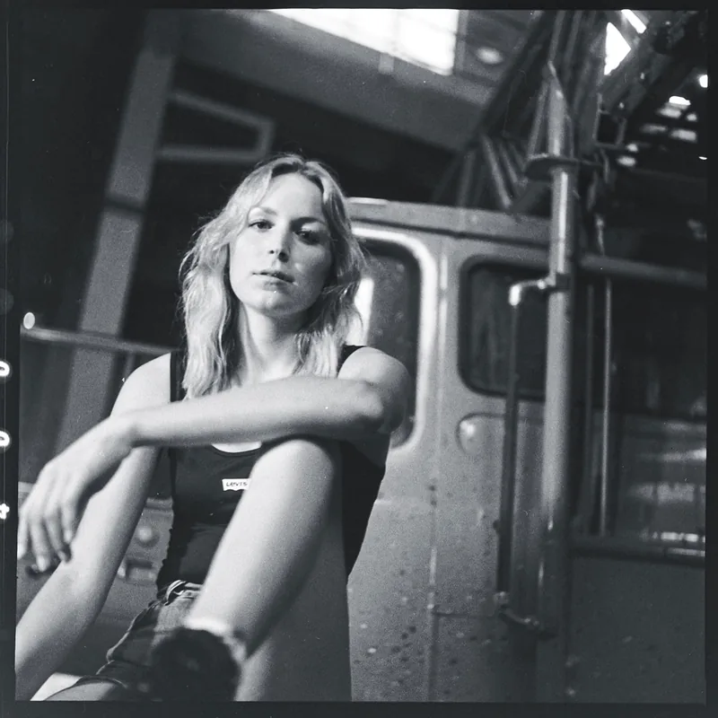 Analoges Schwarz-Weiß-Portrait einer jungen Frau vor einem metallischen Hintergrund.