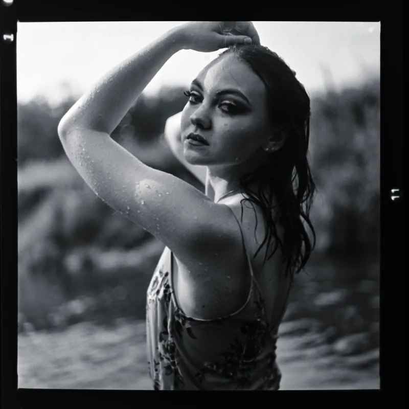 Analoges Schwarzweiß-Portrait einer Frau mit nassem Haar und erhobenem Arm