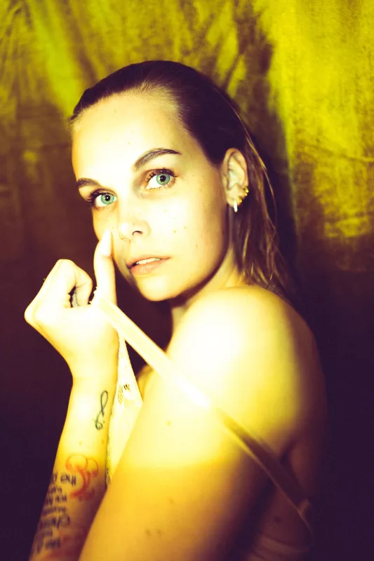 Boudoir-Portrait einer Frau mit direktem Blick vor warmem, gelbem Hintergrund.