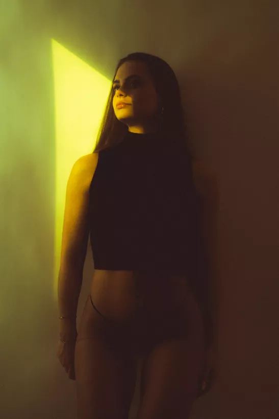 Boudoir-Portrait einer Frau mit markantem gelbem Lichtstrahl im Gesicht.
