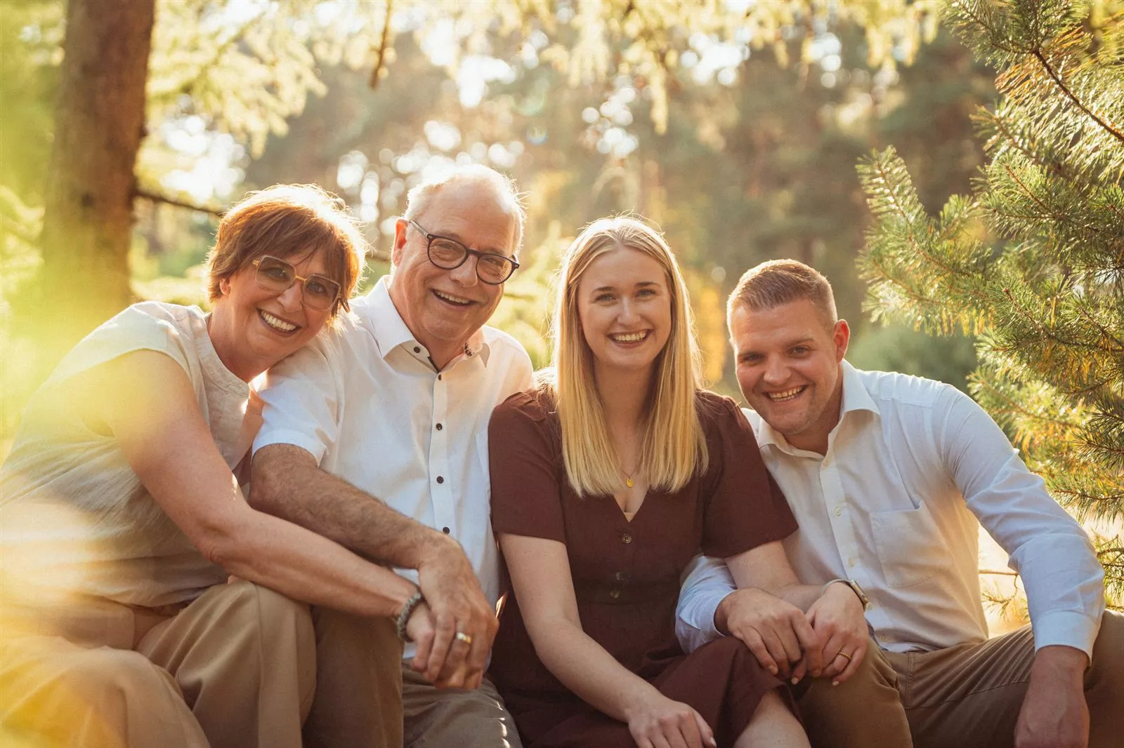 Lachende vierköpfige Familie in einer sonnendurchfluteten Waldlandschaft