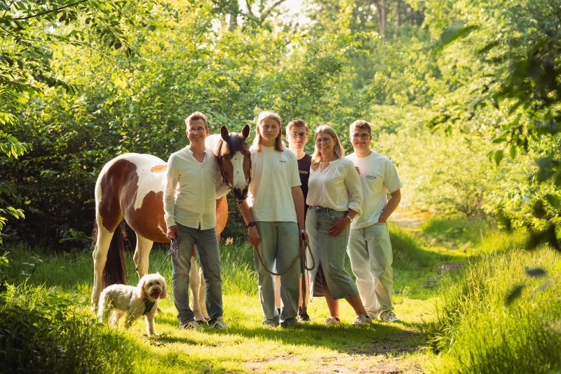 Wunderschönes Familienfoto im Abendlicht im Wald mit Pferd und Hund.