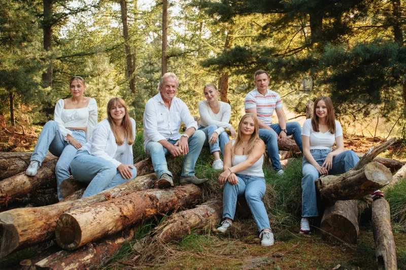 Familienportrait im Wald auf liegenden Baumstämmen