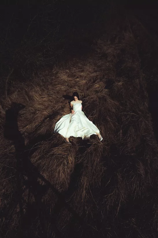 Stimmungsvolles Fine Art Portrait einer Frau in weißem Kleid auf dunklem Gras