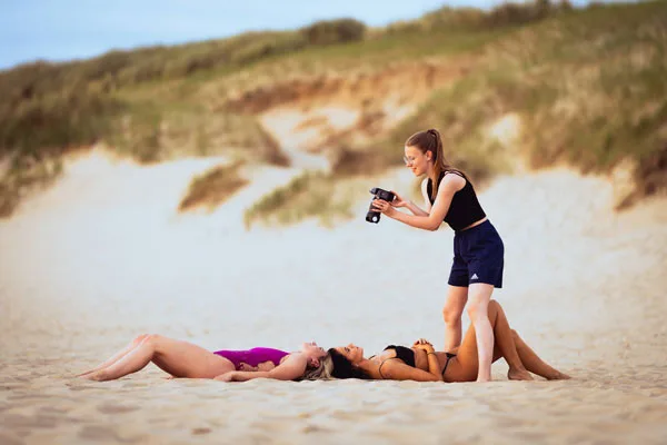 Fotografin beim Shooting zweier im Sand liegender Frauen bei einem Fotoevent.