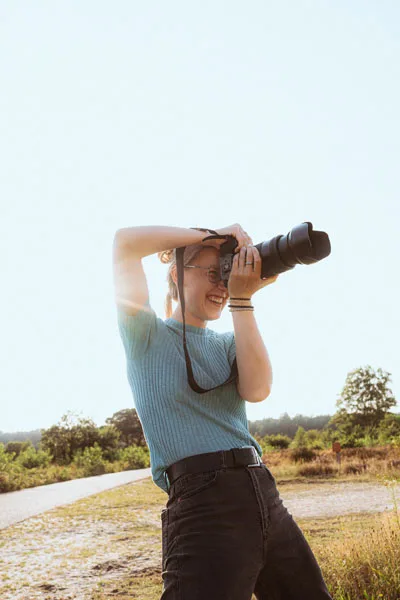 Fotografin mit Kamera in einer sonnigen Sommerlandschaft.