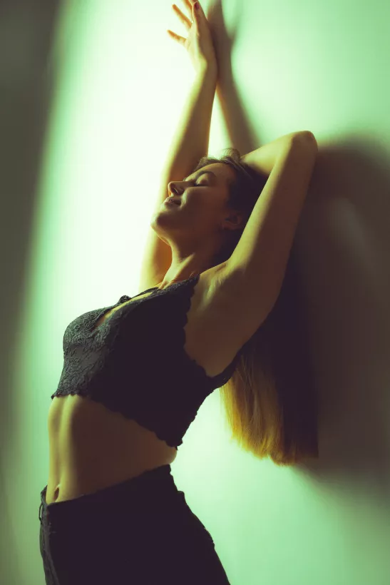 Boudoirfoto einer Frau im Profil mit erhobenen Armen und schwarzem Spitzenoberteil