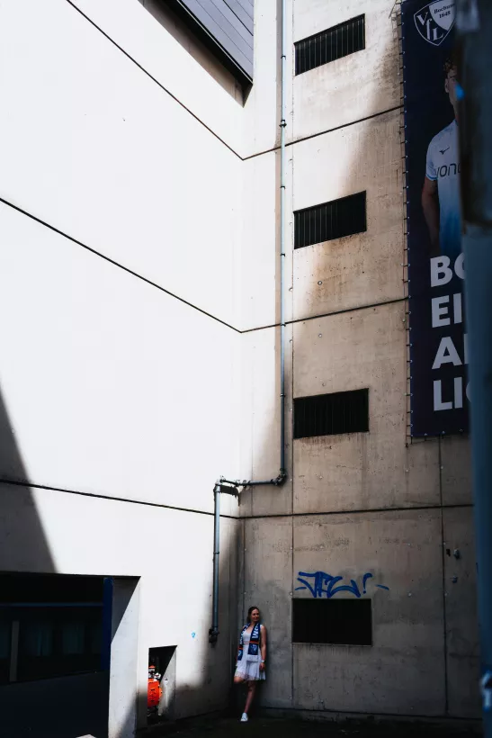 Architekturfoto einer Frau in Weiß vor einer massiven Betonfassade mit markantem Licht- und Schattenspiel