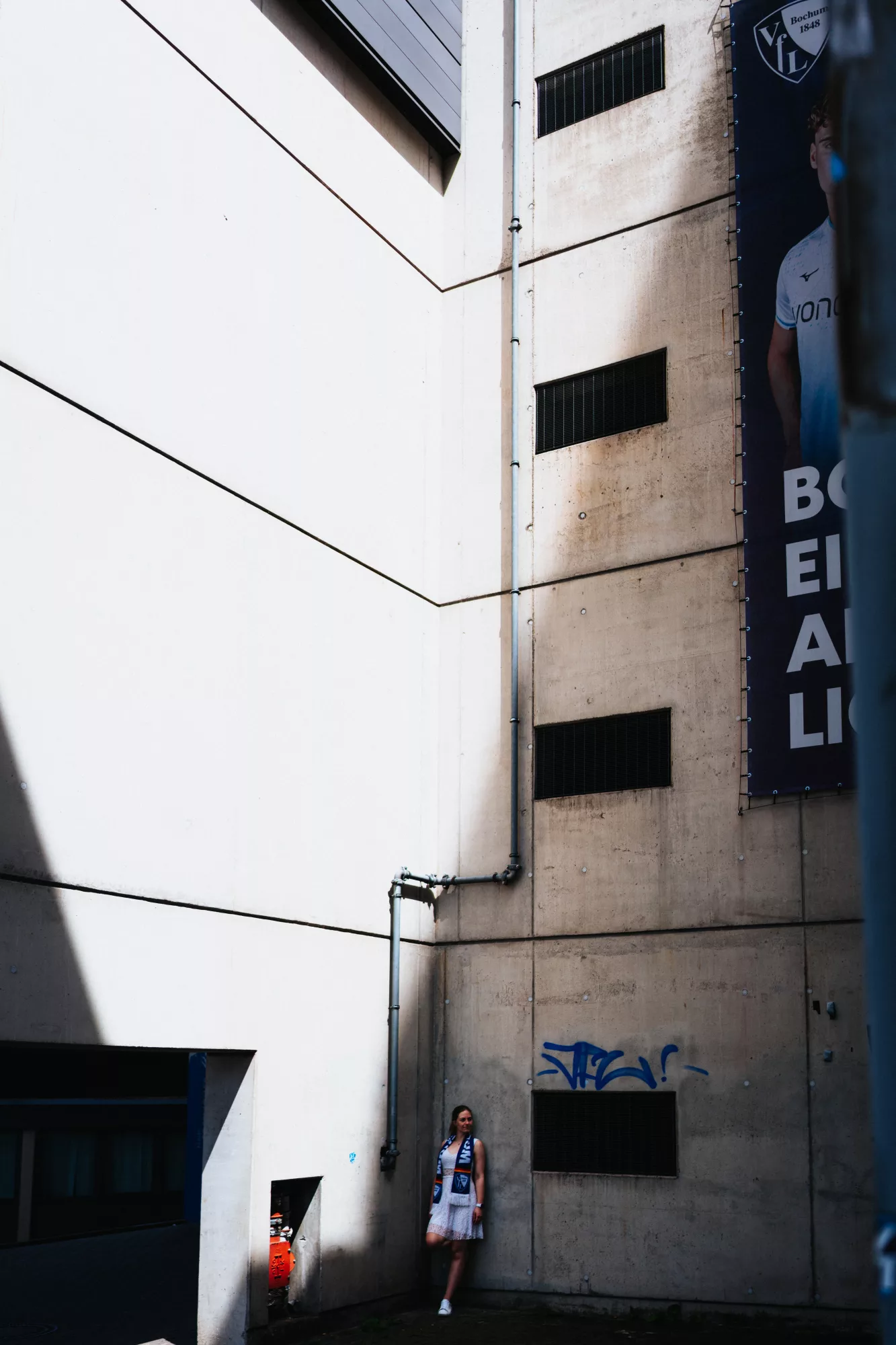 Portrait einer Frau vor einer modernen Betonfassade mit markantem Licht und Schatten