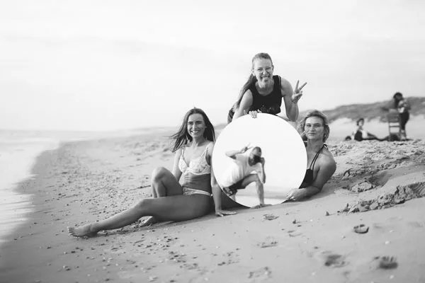 Drei Frauen am Strand mit einem großen runden Spiegel