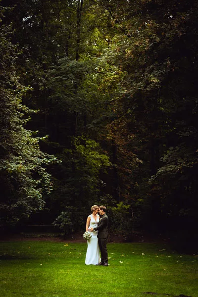 Hochzeitsfoto eines Paares in einer grünen Waldlandschaft.
