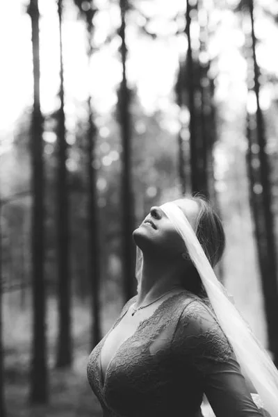 Schwarz-weiß Hochzeitsportrait einer Braut mit Schleier im Wald