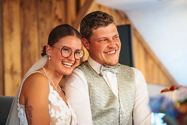 Lächelndes Brautpaar bei einem Hochzeitsportrait vor einer Holzwand