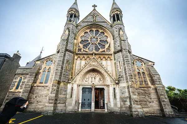 Die imposante Fassade einer gotischen Steinkirche mit einem großen Rosettenfenster und zwei Türmen.