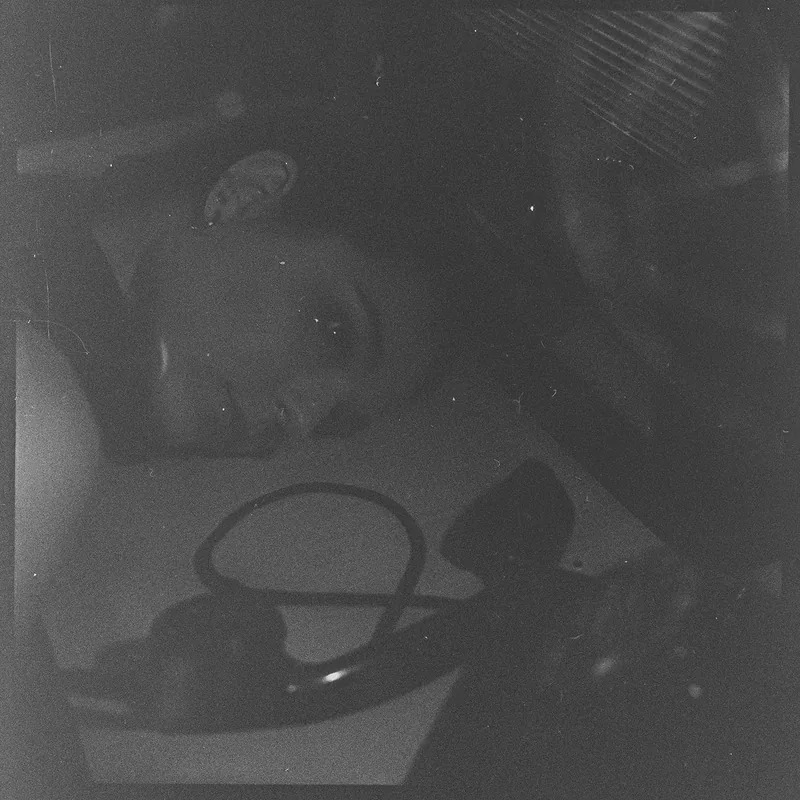 Körniges, analoges Porträt einer Person im Halbschatten mit einem unscharfer Telefonhörer im Vordergrund.