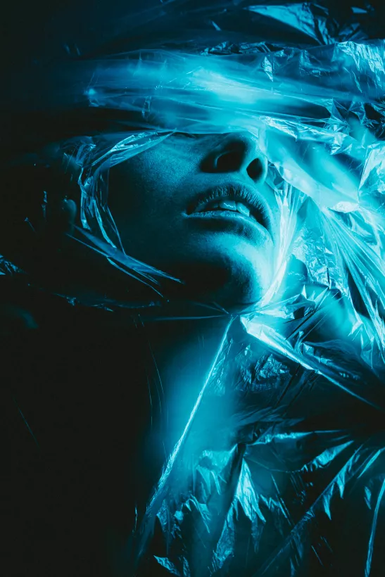 Künstlerisches Porträt eines Gesichts hinter blauer, transparenter Folie