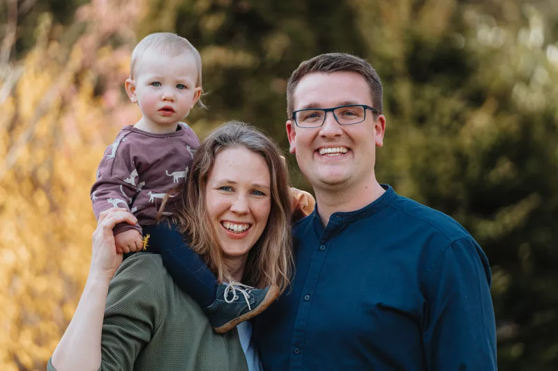 Lachendes Familienportrait eines Paares mit einem Kleinkind in der Natur