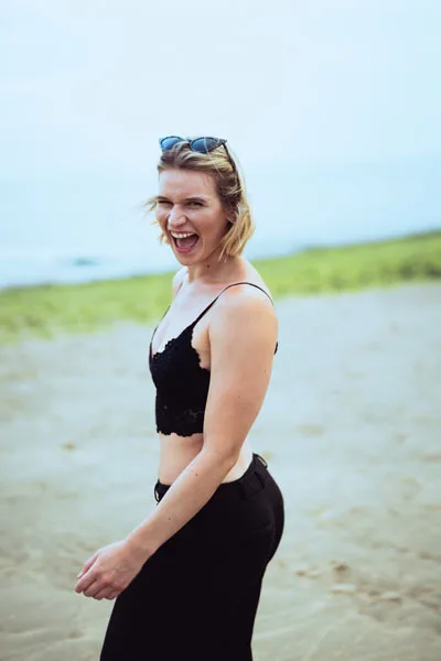 Lachende Frau in schwarzem Spitzenoberteil am Strand