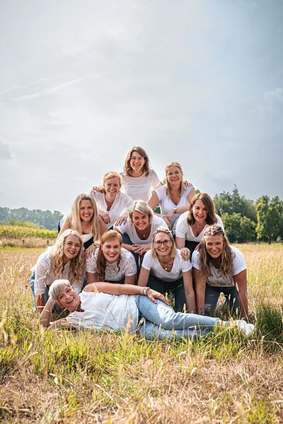 Lachende Gruppe junger Frauen in weißen Oberteilen bei einem Gruppen