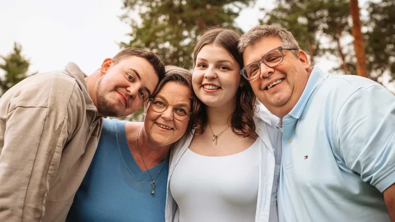 Lachende vierköpfige Gruppe bei einem Familienshooting im Freien.