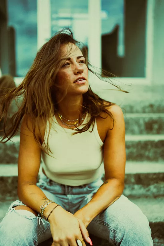 Lifestyle-Portrait einer Frau mit langen braunen Haaren auf Steinstufen