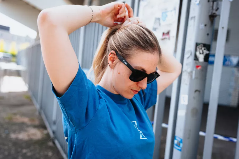 Lifestyle-Portrait einer Frau mit Sonnenbrille beim Hochbinden der Haare