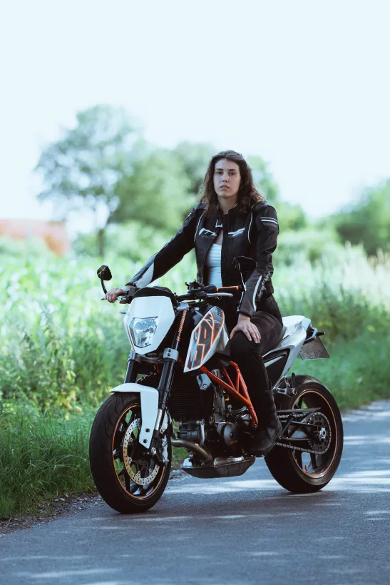 Lifestyle-Portrait einer Person auf einem weißen Motorrad in grüner Umgebung
