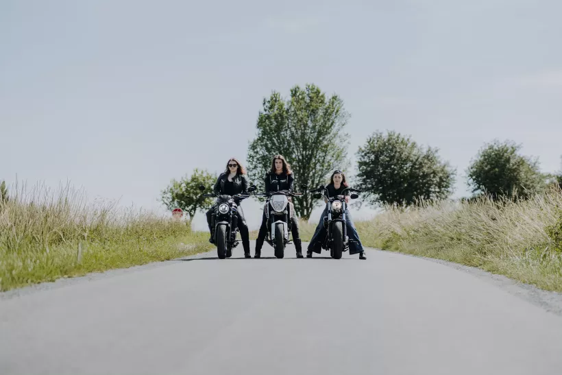 Drei Frauen auf Motorrädern bei einer Fahrt durch die Landschaft im Outdoor-Shooting