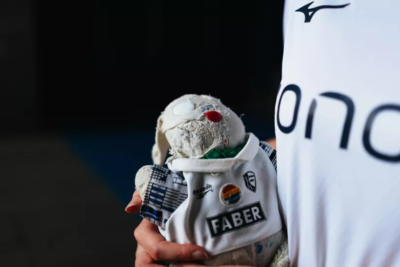 Detailaufnahme eines abgenutzten Plüschhasen mit kleinem Sporttrikot