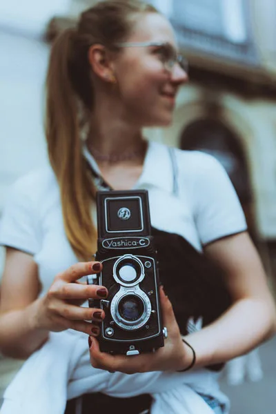 Nahaufnahme einer vintage Yashica-C Kamera in den Händen einer lächelnden Frau.
