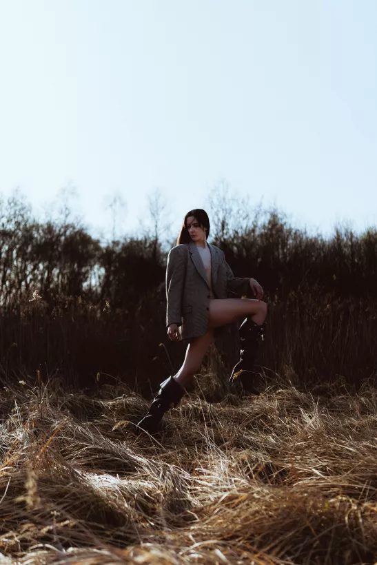 Outdoor-Portrait einer Frau im grauen Blazer in einem Feld mit hohem Gras