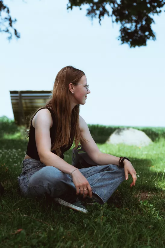 Outdoor-Portrait einer jungen Frau mit Brille auf einer grünen Wiese